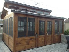 a small wooden building with glass doors on the front and side windows, in a patio area