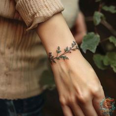 a woman's wrist tattoo with leaves on it