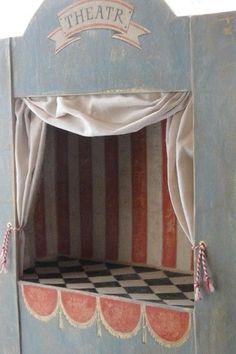 a wooden puppet house with curtains and checkered floor