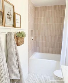 a bathroom with towels hanging on the wall and a bathtub in the shower area