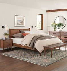 a bed room with a neatly made bed and dressers