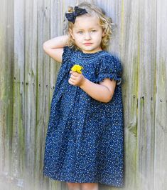 "The \"Blue Navy Blossom Smocked Dress\" is an elegant and classical bishop dress with intricate hand smocked around the neck and the sleeves. Delicate, hand-embroidered blossoms in shades of blue and navy add a whimsical touch. It is perfect for any special occasions and everyday wear as well.  *  100% Cotton *  Handmade *  Buttons at the back *  Soft cotton, comfortable, and ready to play *  Hand wash or machine wash on a delicate setting We are based in Sydney, New South Wales, Australia. We Blue Smocked Dress With Puff Sleeves And Ruffles, Blue Smocked Dress With Flutter Sleeves And Ruffles, Cotton Smocked Dress With Flutter Sleeves, Blue Puff Sleeve Smock Dress, Blue Smock Dress With Puff Sleeves, Blue Smocked Dress For Garden Party, Blue Floral Print Cotton Smocked Dress, Blue Smocked Dress With Flutter Sleeve For Summer, Blue Summer Smocked Dress With Flutter Sleeves