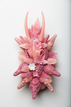 a pink brooch with flowers and leaves on it's back end, against a white background