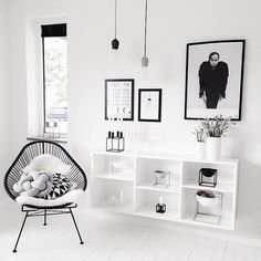 a white room with black and white pictures on the wall, a hanging chair in front of a book shelf