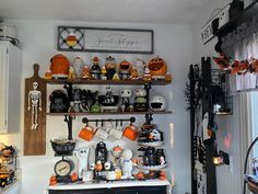 a kitchen decorated for halloween with pumpkins and other decorations on the shelf above it