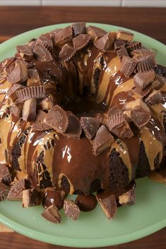 a chocolate bundt cake with peanut butter and oreo pieces on top, sitting on a green plate