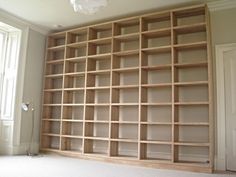 an empty bookcase in the corner of a room with white walls and carpeting