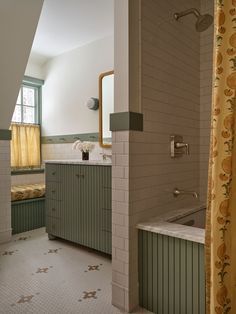 the bathroom is decorated in green and white tile, with yellow shower curtains on either side