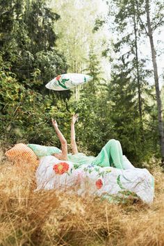 a woman laying on her back in the grass with an umbrella above her head and holding a frisbee