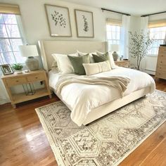 a large white bed sitting on top of a wooden floor next to two dressers