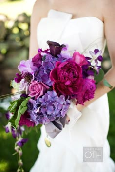 a bride holding a bouquet of purple flowers