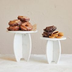 two white pedestals with donuts and cookies on them