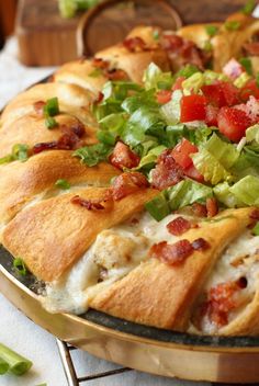 a pizza sitting on top of a pan covered in lettuce and tomato slices