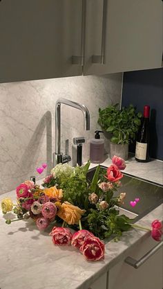 flowers are sitting on the kitchen counter next to the faucet and wine bottle