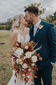 a bride and groom kissing in the field