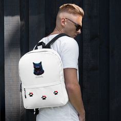 a man wearing a white backpack with an image of a cat on it