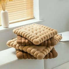 three pillows stacked on top of each other in front of a window