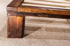 a wooden bench sitting on top of a carpeted floor next to a white rug