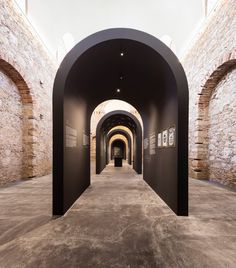 an arched hallway with black walls and pictures on the wall