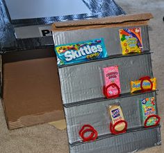 an open cardboard box with candy and snacks on it sitting on the floor in front of a television