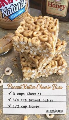 peanut butter cheerio bars stacked on top of each other with a jar of honey in the background