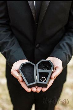 a man in a suit holding an open ring box