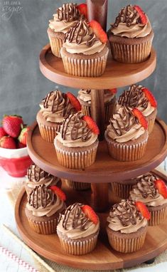 cupcakes with chocolate frosting and strawberries are on a wooden tray, ready to be eaten