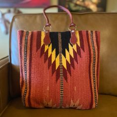 a red and yellow bag sitting on top of a brown couch