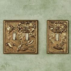 two switch plates with flowers on them are sitting side by side against a green wall