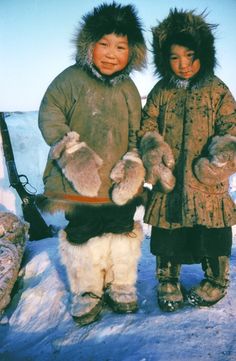 two young children standing in the snow holding stuffed animals