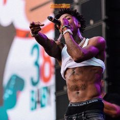 a man with dreadlocks on his head singing into a microphone at an outdoor concert