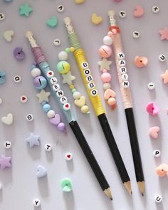 three pencils are lined up in the shape of hearts and stars, with words written on them