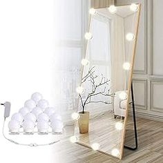 a large mirror with lights on it in a room next to a table and chair