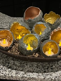 candles are placed in an egg shell on a plate with rocks and gravel around it