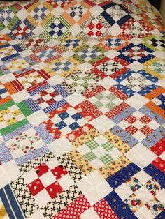 a colorful quilt is laying on top of a bed