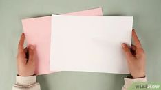 two hands holding up pink and white papers