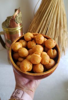 a person holding a bowl filled with food next to a broom and potted plant