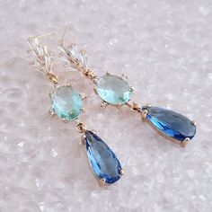 "Gold Blue Earrings for brides, weddings and bridal showers. The perfect gift earrings for bridesmaids, mother of the groom, or mother of the bride. Find earrings for bridal bachelorette party or other special occasions here. A pretty pair of classic teardrop glass crystal earrings embellished with twinkling cubic zirconia crystals on a gold finish. These dainty CZ  and glass crystal drop earrings make a gorgeous bridesmaid gift and make a timeless wedding earring too. Blue glass crystals add a fun pop of color and a great way to sneak in a \"something blue\" into your bridal or bridesmaid ensemble. Simply stunning!  These beautiful blue statement earrings will complement any bridal style and make the perfect gift for bridesmaids too. The Details: * Made with premium quality crystals * Sto Elegant Blue Drop Crystal Earrings, Blue Crystal Drop Earrings For Formal Occasions, Blue Drop Bridal Earrings For Formal Events, Blue Drop Bridal Earrings For Formal Occasions, Blue Drop Earrings For Bridal Formal Occasion, Blue Drop Earrings For Formal Bridal Wear, Blue Drop Bridal Earrings, Blue Dangle Crystal Earrings For Formal Occasions, Elegant Blue Crystal Earrings For Wedding