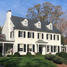 a large white house with black shutters on the front and side windows is shown