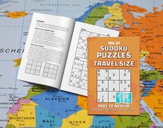 the sudoku puzzles travel size book is open on a world map and it's contents are laid out