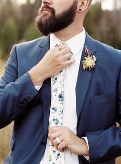 a man in a blue suit adjusting his tie