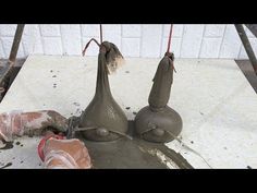 two clay sculptures sitting on top of a cement slab