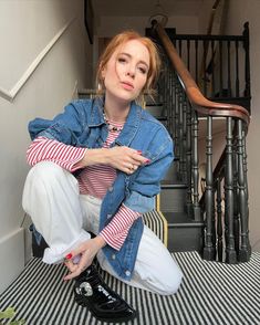 a woman sitting on the ground in front of stairs with her hand on her knees