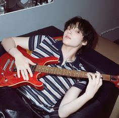 a person sitting on a couch with a guitar