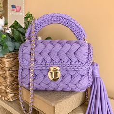 a purple handbag sitting on top of a table next to a basket with flowers