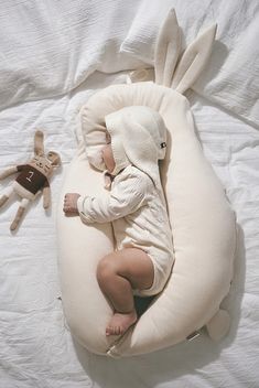 a baby is sleeping on a pillow with a stuffed animal next to it in the shape of a bunny