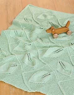 a wooden toy dog sitting on top of a crocheted blanket that is laying on the floor