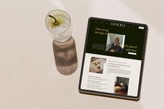 a tablet with a drink on it next to a small glass filled with something else