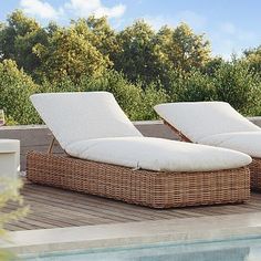 two wicker chaise loungers next to a swimming pool