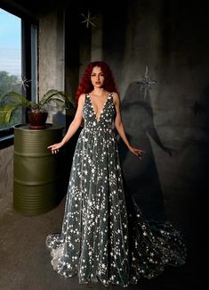 a woman with red hair wearing a black and white dress standing in front of a window